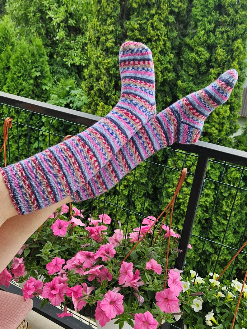 A pair of vibrant knee-high knitted socks featuring an array of colorful patterns, showcasing their cozy texture and unique design.